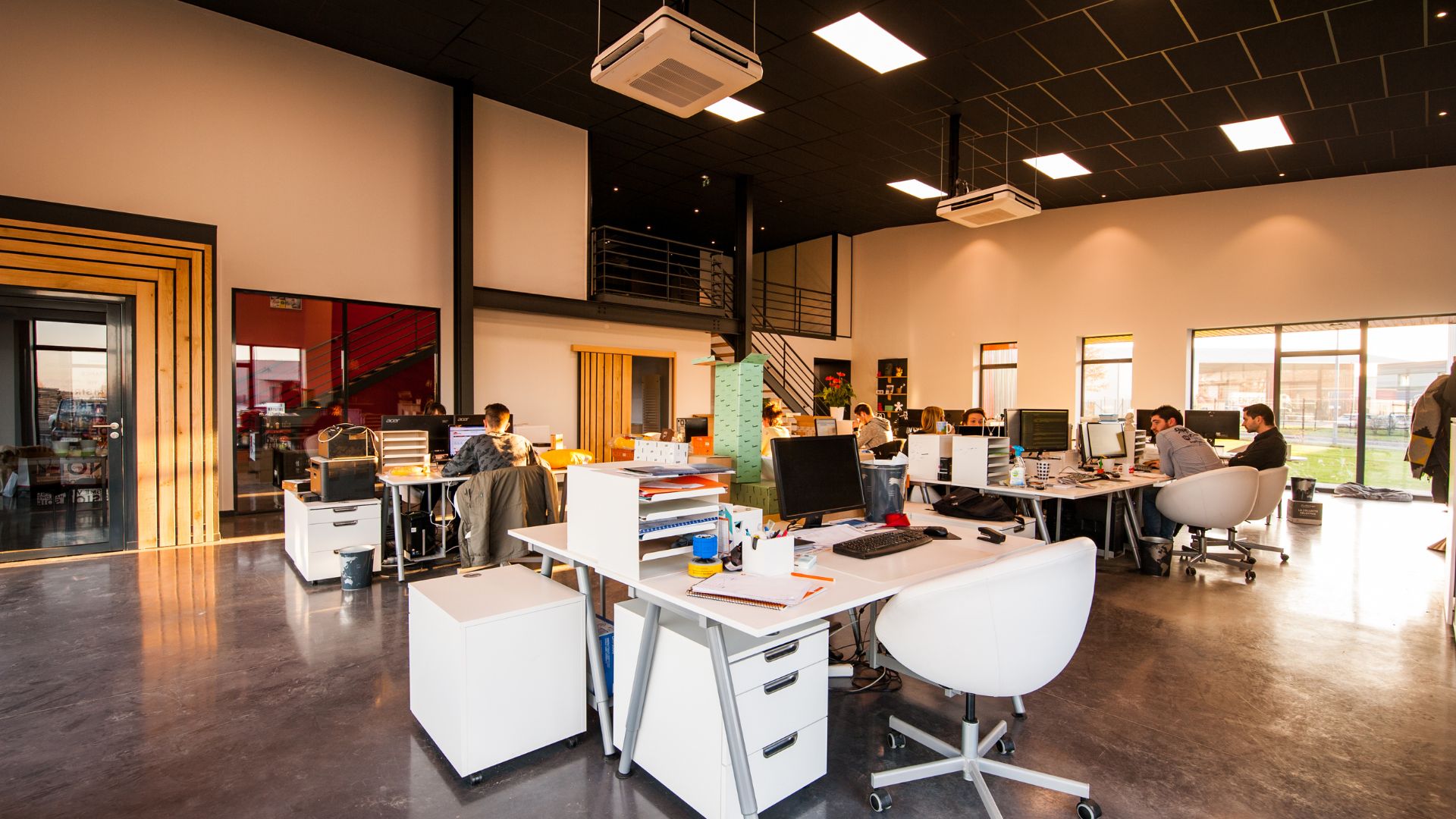 Modern open-plan office with workers at desks and large windows