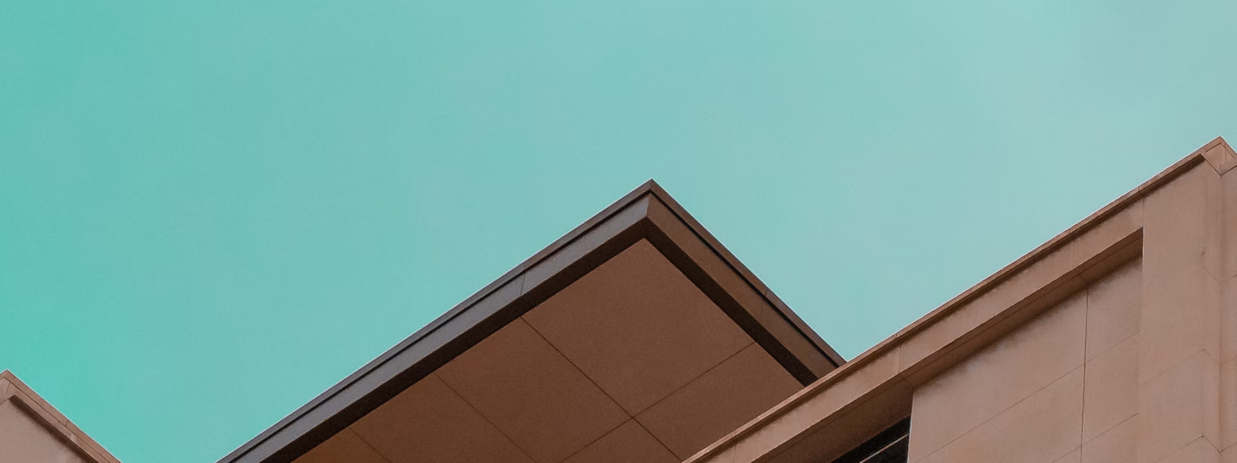 Modern building rooflines against a teal sky with geometric architectural angles